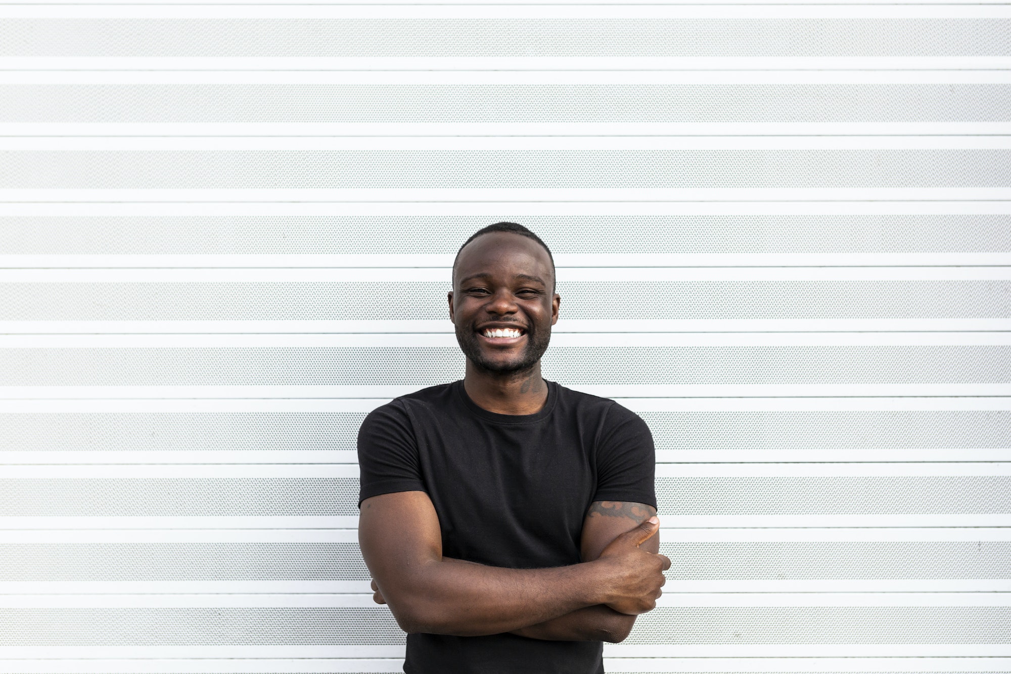 Cheerful black male standing near striped wall