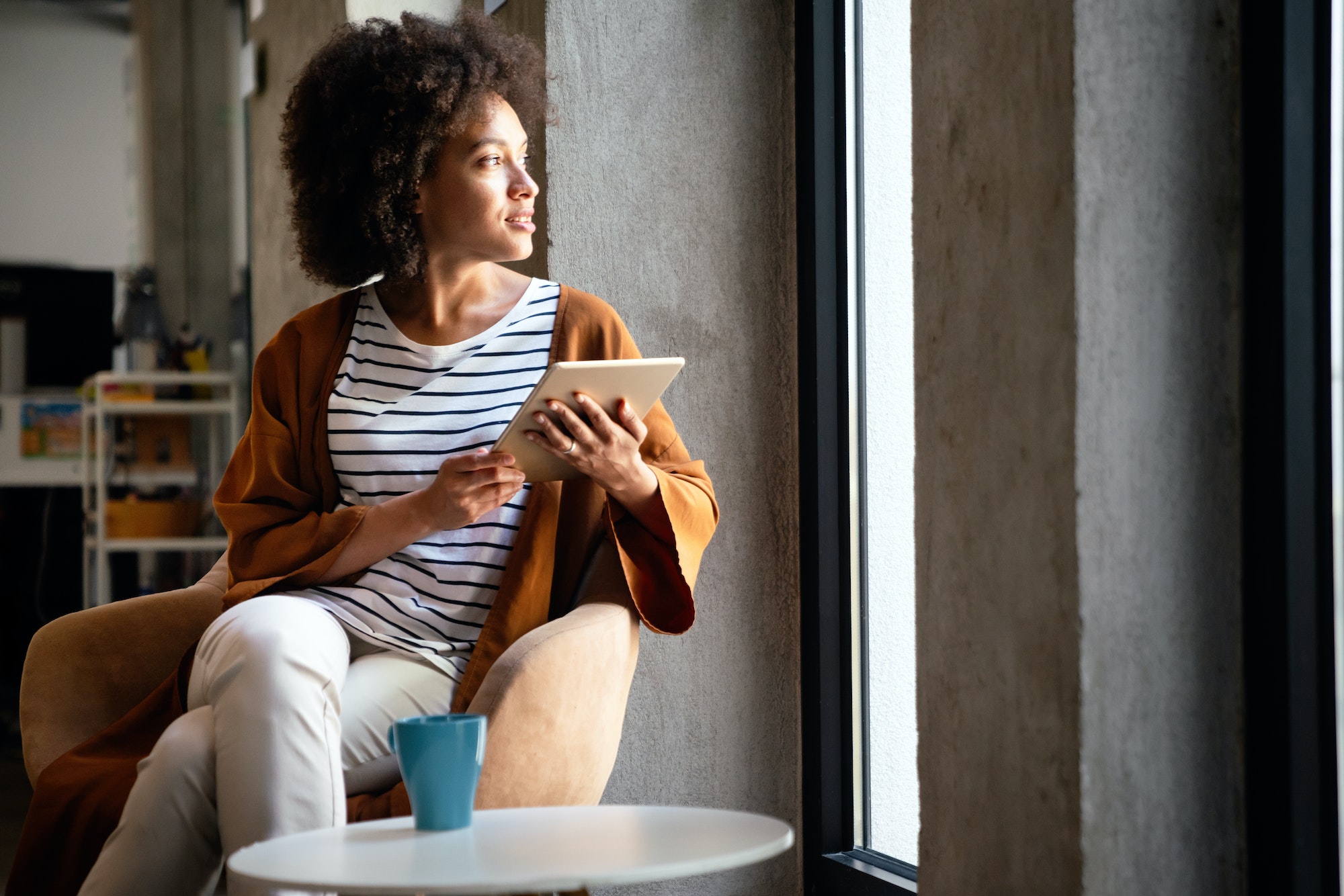 Enjoying coffee break with tablet. Attractive black business woman working on digital tablet