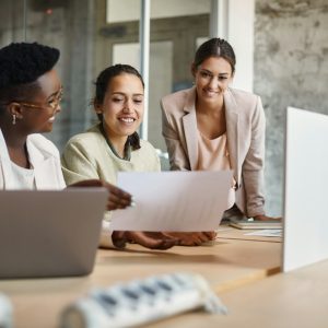 Happy female entrepreneurs cooperating while analyzing business plans in the office.